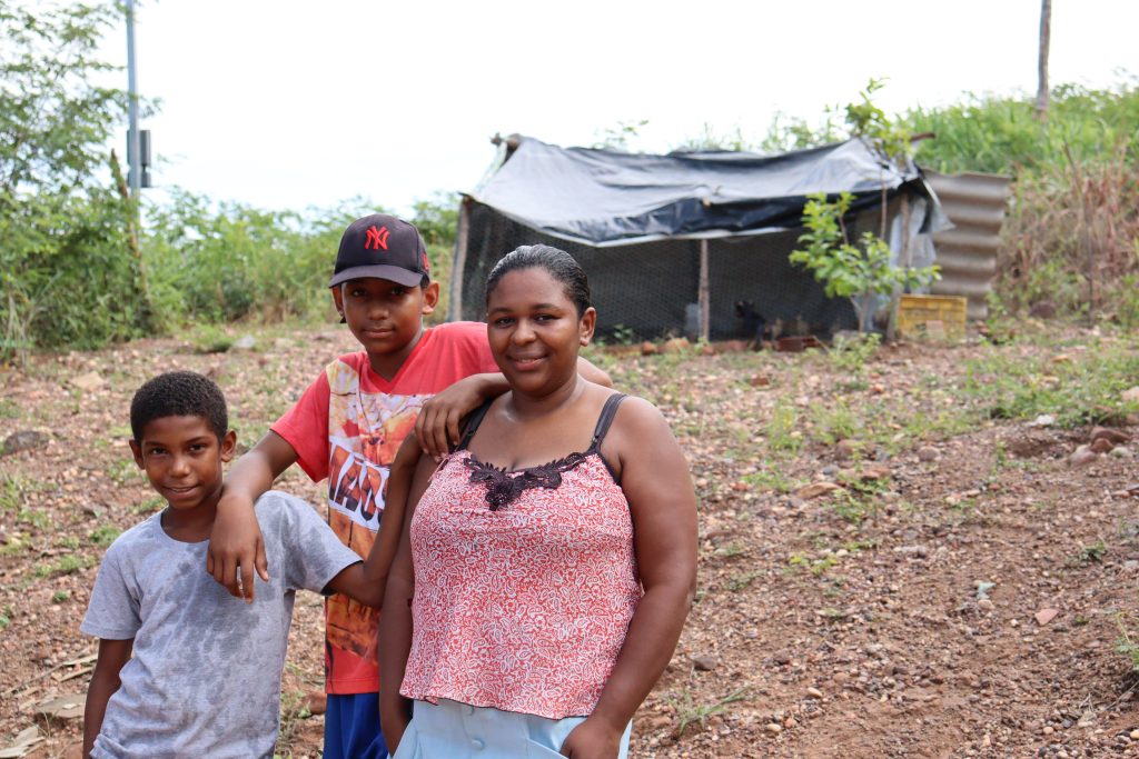 Imagem mostra mulher com os filhos e galinheiro ao fundo