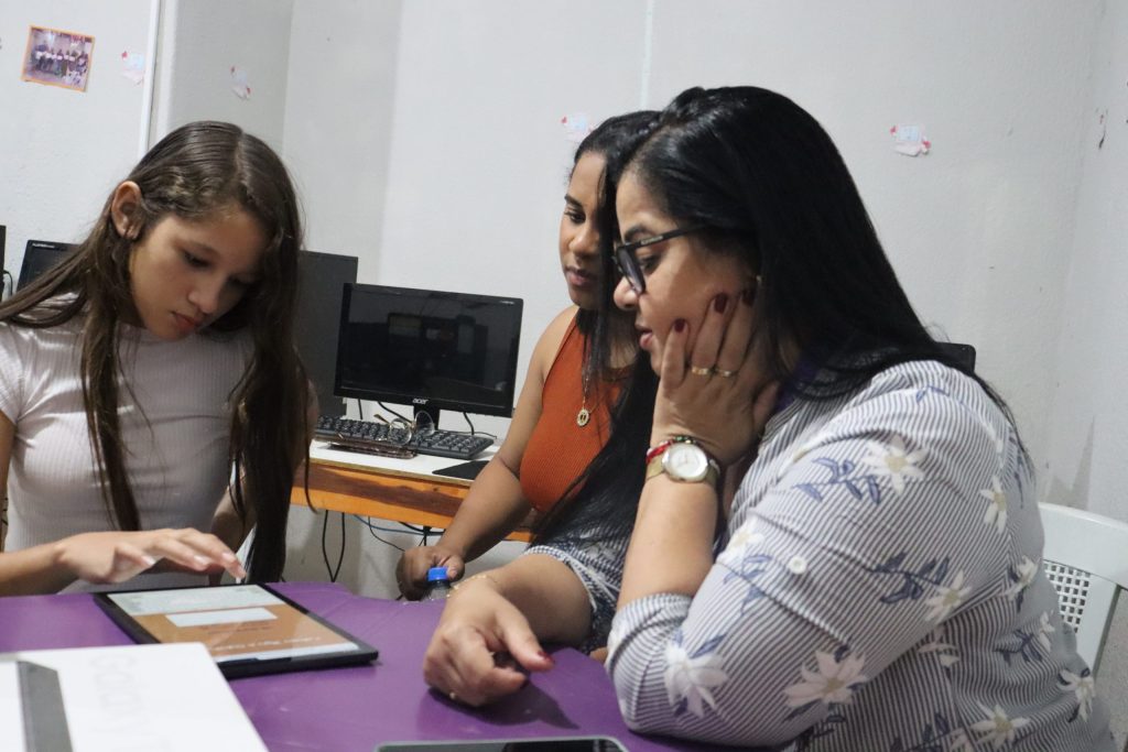 Ilustra criança acessando internet acompanhada por educadoras