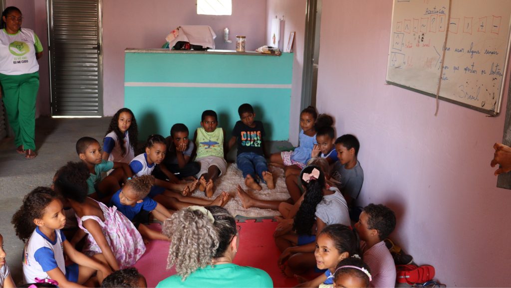 Crianças reunidas em torno de educadora