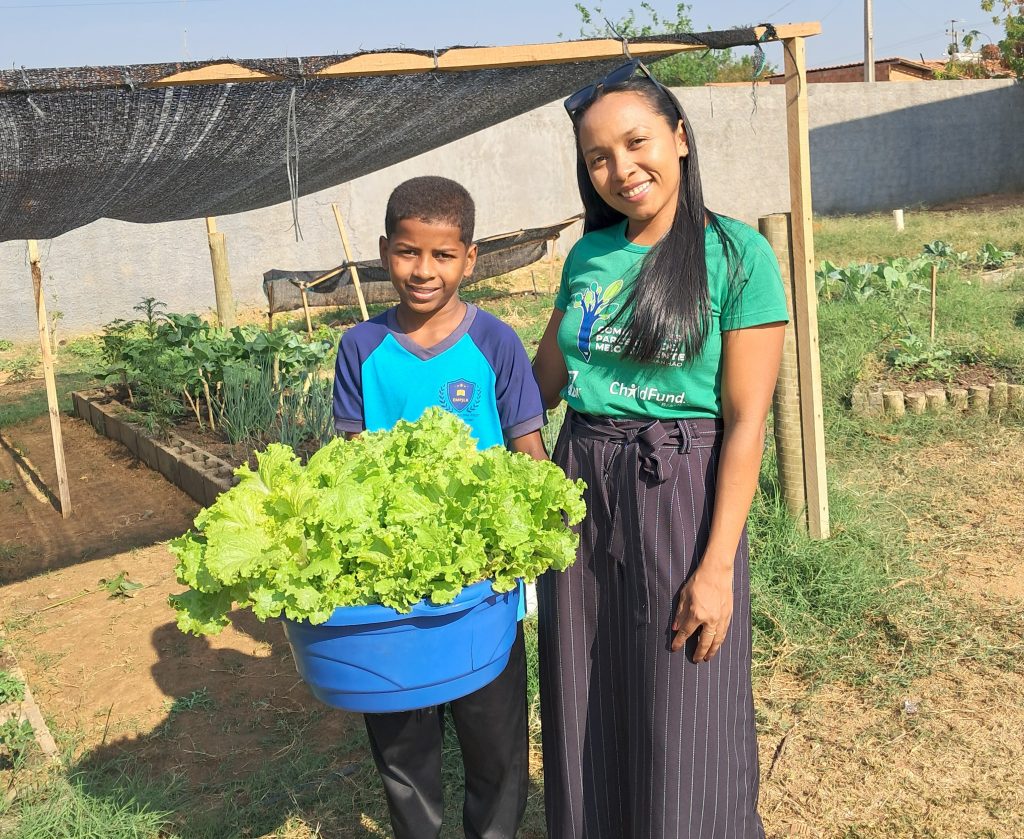 menino com verduras com funcionária do ChildFund